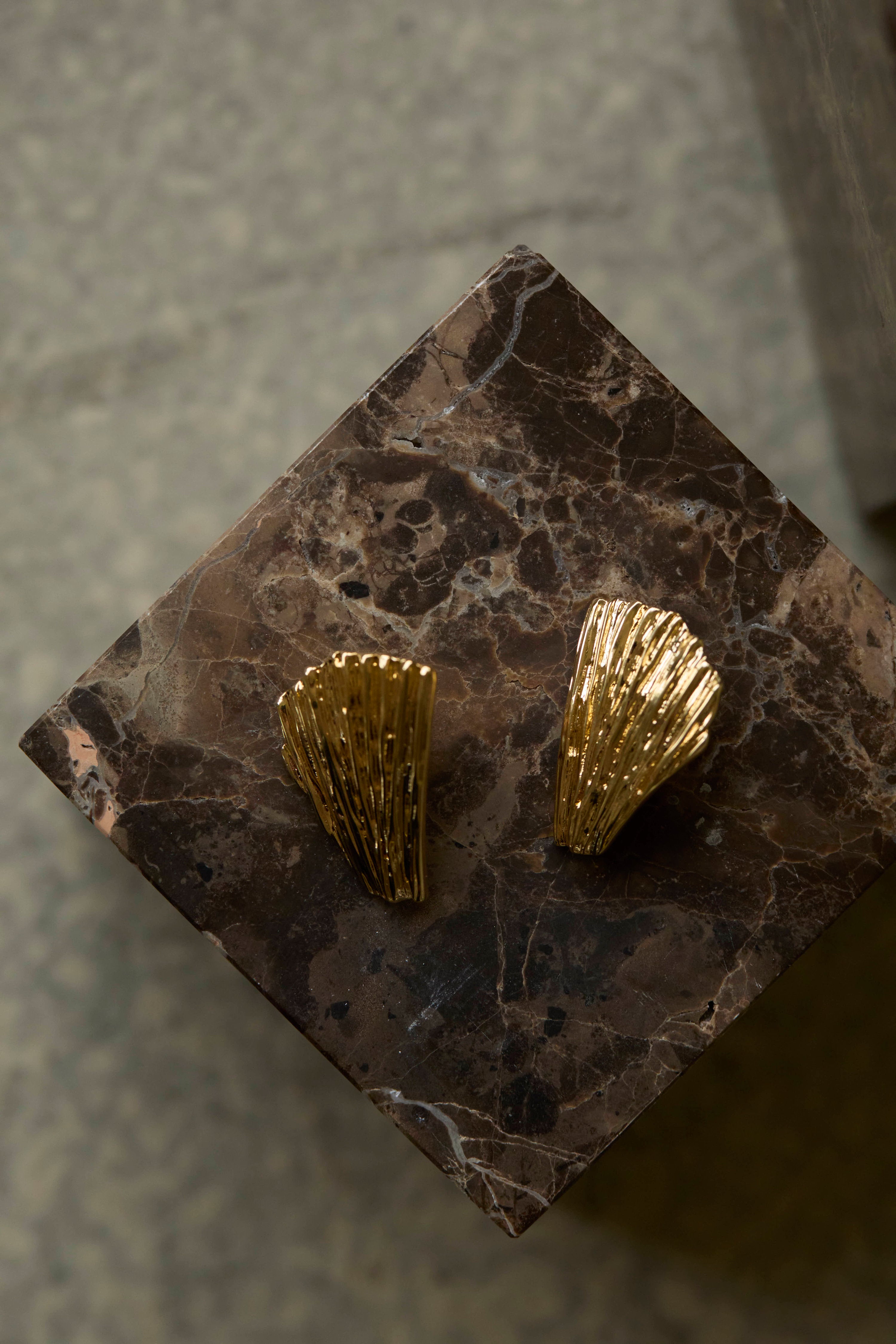 Gold shell-shaped earrings earrings on a marble surface Neréa earrings