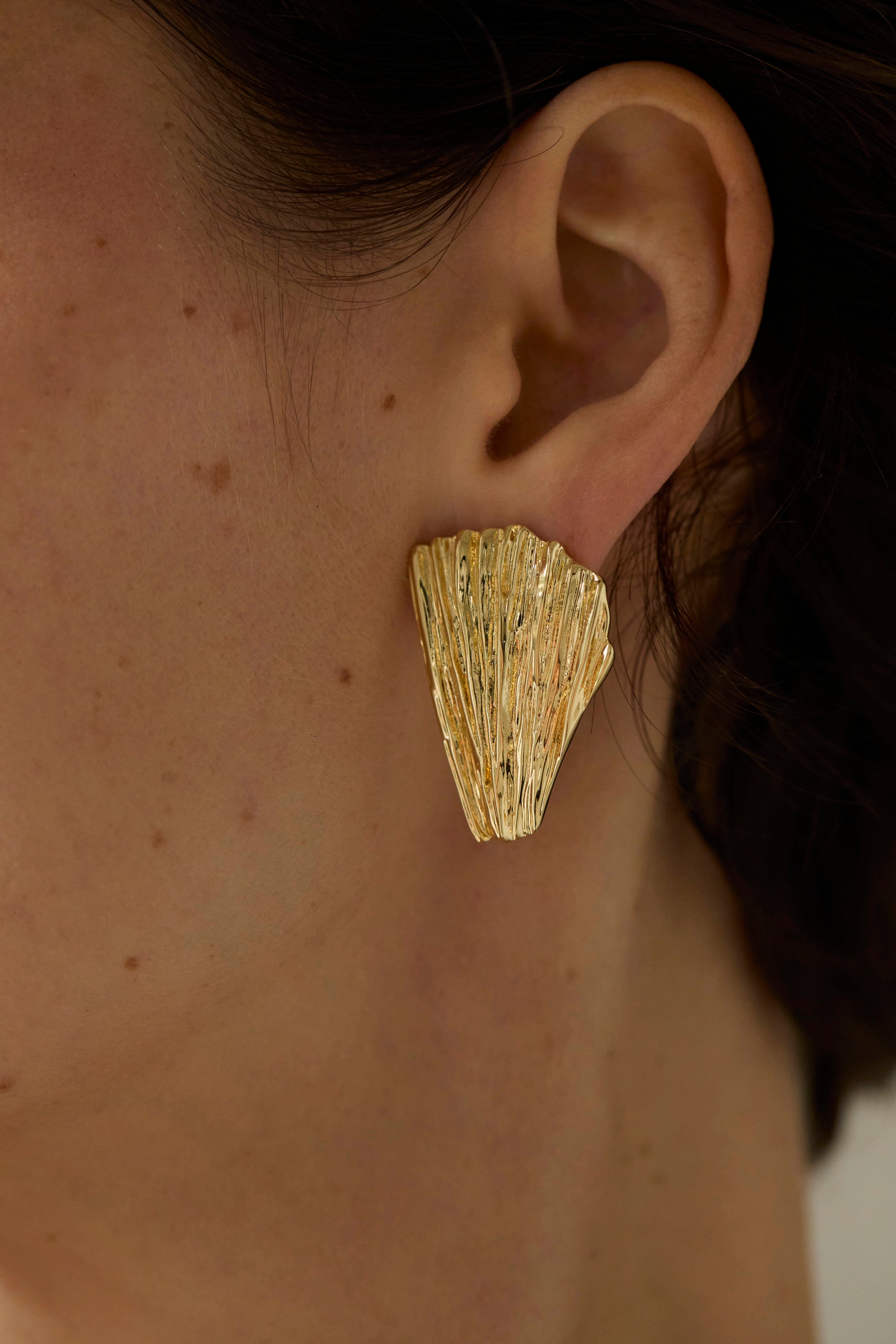Gold gold shell-shaped earrings worn by a person Neréa earrings 
